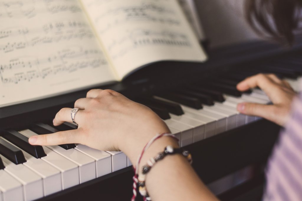 A student playing piano with sheet music
